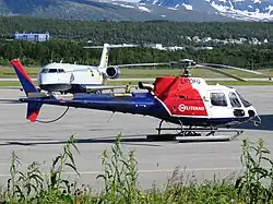 Helicopter coloured red, white, and blue. The text "Helitrans" is written on the side of the aircraft, with "LN-OFG" written above