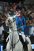 A running martingale helps with this resisting horse
