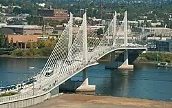 An aerial view of a MAX light rail train and TriMet busses crossing the Tilikum Crossing cable-stayed bridge