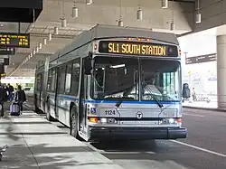 A silver-painted bus curbside at an airport