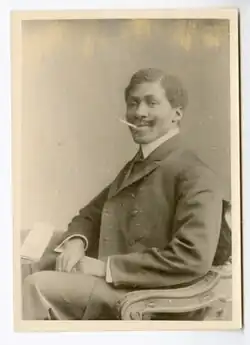 Mandenga Diek wearing an elegant suit, with an upturned cigarette