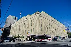Panorama of the arena exterior with beige-coloured bricks and street scene at a downtown intersection
