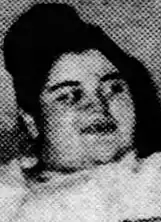 A newspaper photograph of a young white woman with dark hair in a top bun.