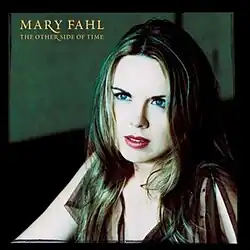 The artist, Mary Fahl, is sitting on the right side of the image staring off to the left of the camera. Behind her is the blurred background of a green wall. The artist and the title appear in yellow letters on the top left.