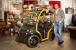 Matteo Maestri, CEO of Estrima, standing beside a Birò microcar in what seems to be an apartment