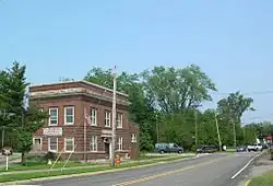 A large square red brick building on a triangular lot