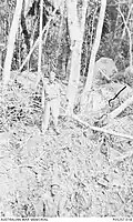 Legge stands above a bomb crater on North Brook Island, Jan 1944