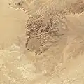 The Tin Bider crater in Algeria, producing the reverse illusion. The crater rises above the surrounding terrain, however the position of the sun makes it appear to be below it.[4]