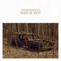 The shell of a car in the middle of barren trees
