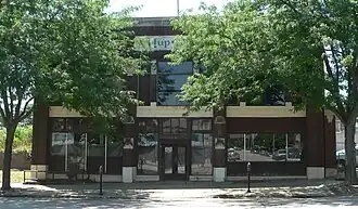 Two-story brick building with stone trim, "Hupmobile" inscribed near top center