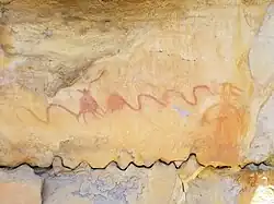 A red serpentine line with unidentified embedded forms, an orange circle, and an orange anthropomorphic figure.