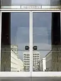 Entrance 'L' at the palazzo. In the reflection of the door the Colosseo Quadrato can be seen reflected.