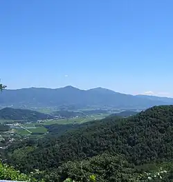 View of across narrow valleys of farm fields interspersed with forested mountains