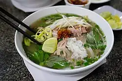 a bowl of brightly coloured soup with vegetables and meat in it