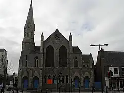Stone church with blue stained glass windows and a steeple.