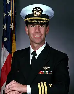 A color portrait photo of a smiling white man, looking into the camera, wearing a Navy admiral's uniform
