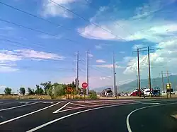 A two lane road with a separate turning lane, with a red octagonal stop sign in the middle.
