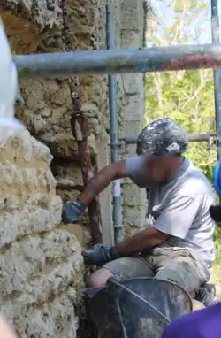 A mason gives a demonstration to volunteers during the restoration of the wall.