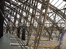 The glazed roof and vertical struts supporting the fluted aluminium ceiling, beneath the wooden floor