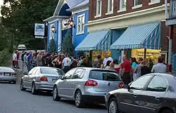 A crowd of patrons standing on the sidewalk outside a movie theater.