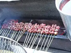 Raw sate kambing (lamb satay) being grilled
