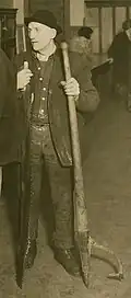 Man holding a crosscut saw and a peavey.