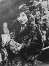 A smiling Japanese woman wearing a hat and a fur coat