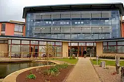 Modern office development in mostly glass with approach paths having a side ornamental water feature on a bright day