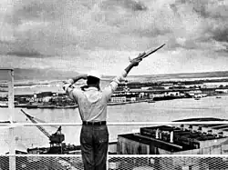 A signalman sends a semaphore message from a Pearl Harbor Control Tower, c. 1960.