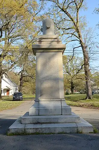 Rectangular stone monument with inscriptions on sides and decorative element atop