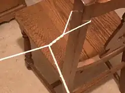 A section of string contains a number of twists which lead to a loop secured to the back of a chair.