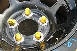 Five yellow lug nuts for use on a car with wheels studs