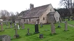 A small stone church with graves in the foreground