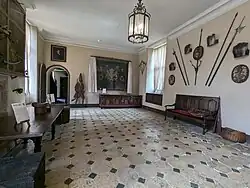 A large room decorated in medieval style with wooden furniture, textiles and antique weapons