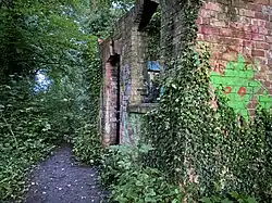 The graffitied ruins of a Parish House. Ivy is present and covers the ruin.