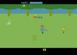 A video game sprite representing Leatherface, facing a sprite representing a possible victim. Below Leatherface is a sprite of a bush, to the left of the screen is a sprite of a cow skull. The background is lined with four trees, and distant house and car sprites.