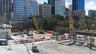 Construction site with an excavator sitting there. Excavation of the station box has begun.