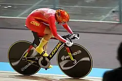 A photo of Zhong Tianshi, dressed in red, track cycling at a race
