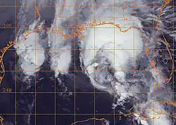 Black and white satellite image of a disorganized tropical cyclone in the Gulf of Mexico. Most of the storm's clouds are displaced to the north in an arc shape.