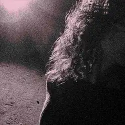 A grainy and purple-tinted image of a light shining on a person's hair