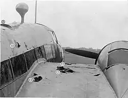 a black and white photograph of a portion of the fuselage and wing of an aircraft with holes that served as foot and hand holds