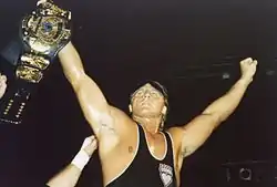 Wrestler Owen Hart holds up the "Winged Eagle" championship belt