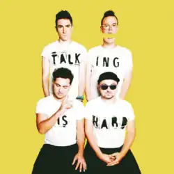 The band members of Walk the Moon wear white t-shirts that spell out Talking Is Hard in front of a yellow backdrop.