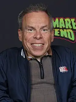 A man smiling in front of a poster