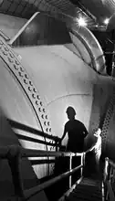 A worker stands by the 30 ft (9.1 m) diameter Nevada penstock before its junction with another penstock that delivers water to a turbine.