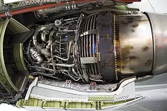 This view shows the way turbine blade tip clearance is controlled actively (passive control is by material selection and internal air system cooling) using cooling-air tubes (for low pressure turbine blade tip to shroud clearance control) which circle the iridescent turbine casing on a CFM International CFM56. Cooling air manifold (smooth flat surface), to left of LPTCC tubes, for high pressure turbine blade tip clearance control. Active control comes from activation of valves which supply cooling air to the tubes at appropriate flight conditions.