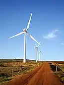 Wind turbines beside a red dirt road