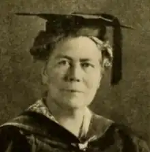 An older white woman in academic robes and a mortarboard cap, from 1920 yearbook