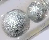 Potassium pearls under paraffin oil. Size of the largest pearl is 0.5&nbsp;cm.