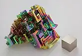 Bismuth in crystalline form, with a very thin oxidation layer, and a 1&nbsp;cm3 bismuth cube